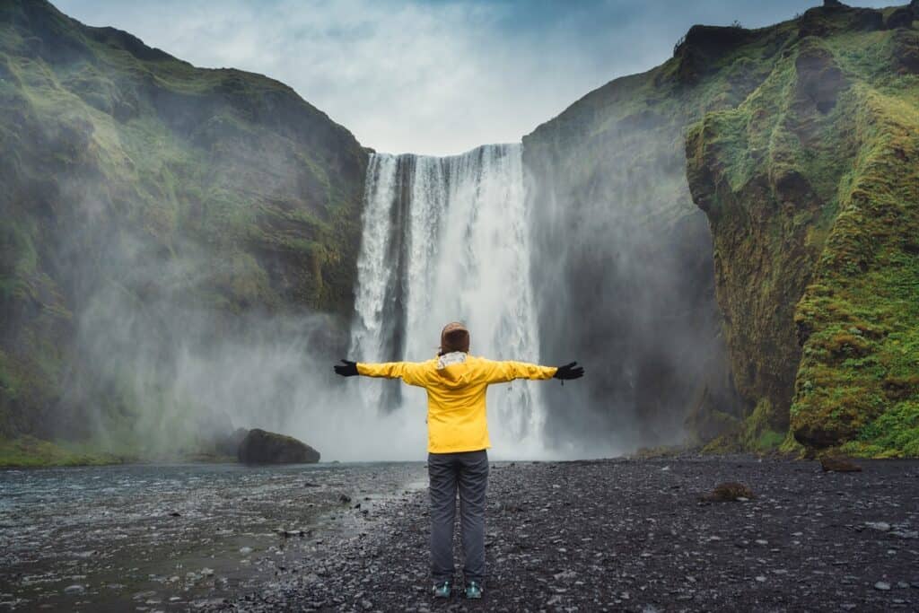 voyageur devant la cascade Skogafoss en Islande