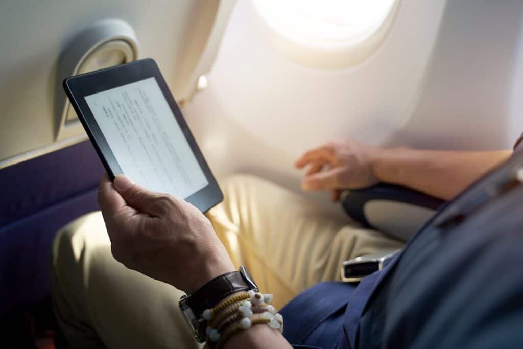 homme lisant sur une liseuse électronique en avion