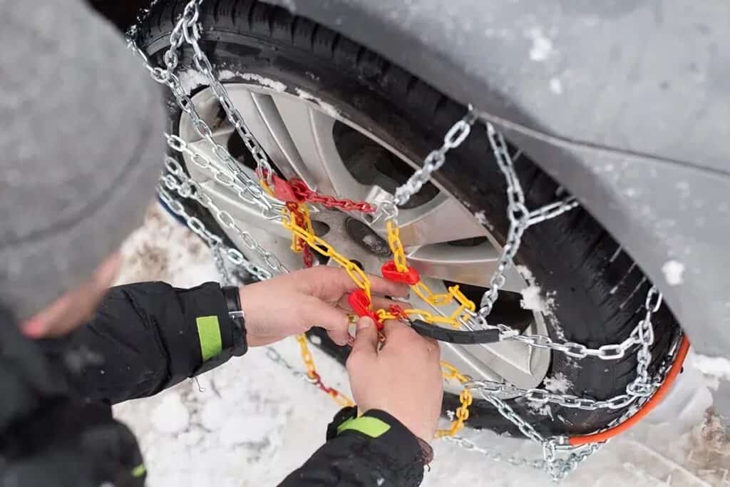 homme installe une chaine à neige