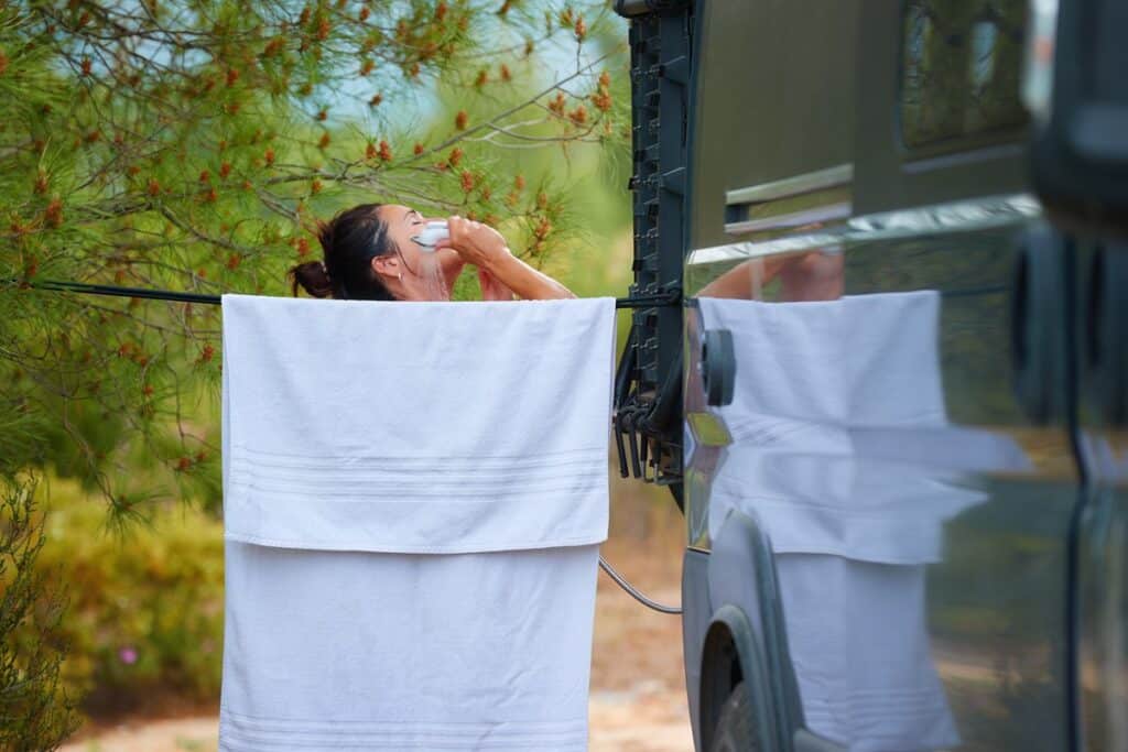 femme qui se douche près d'un van aménagé